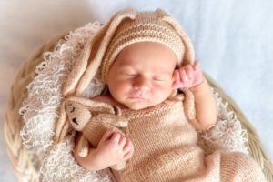 Ein schlafendes Baby mit einem Stoffhasen mit Hasenmütze.