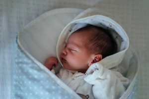 Ein Baby schläft in einem blauen Fußsack mit weißen Pünktchen
