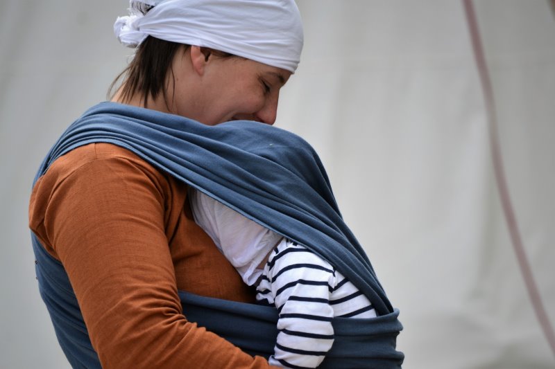 Mama mit Säugling im blauen Tragetuch