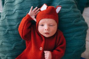 schläfriges Baby im roten Strickanzug