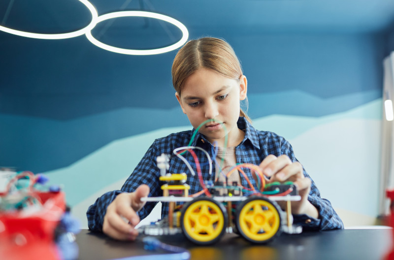 Mädchen mit Experimentierkasten Ein Mädchen staunt über ihr selbstgebautes Auto aus dem Experimentierkasten