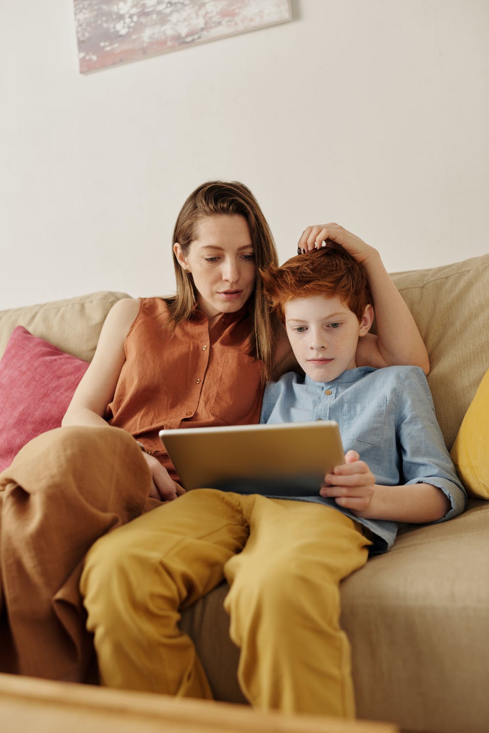 Mama schaut Kind beim Spielen über die Schultern Mama und Sohn sitzen vor dem indertablet