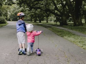 Zwei Kinder fahren mit einem Kinderroller