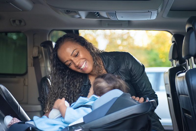 Ein Baby, eine Mutter und ein Autokindersitz. Eine Mutter und ihr Baby in einem Autokindersitz.
