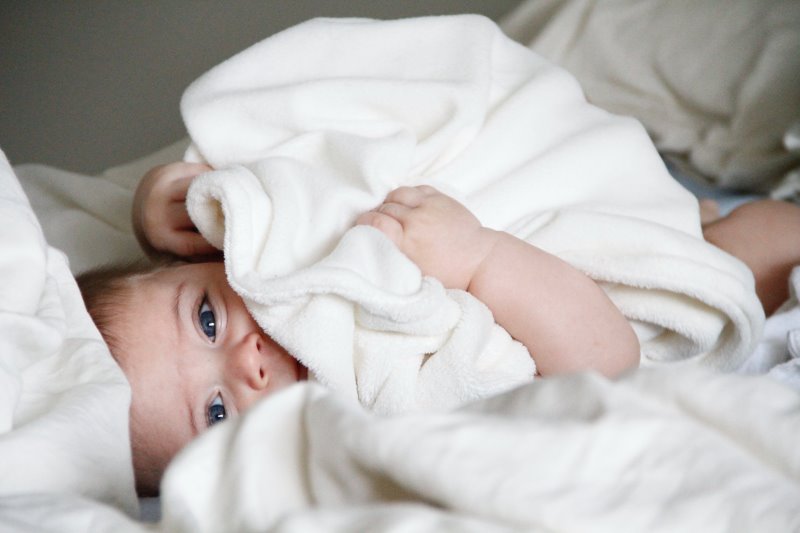 Baby-Badetuch Baby kuschelt mit einem Badetuch Baby kuschelt mit einem Badetuch.