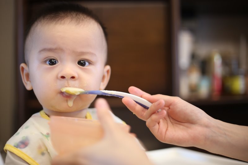Esslernbesteck Baby wird gefüttert Ein Baby wird mit Brei gefüttert.