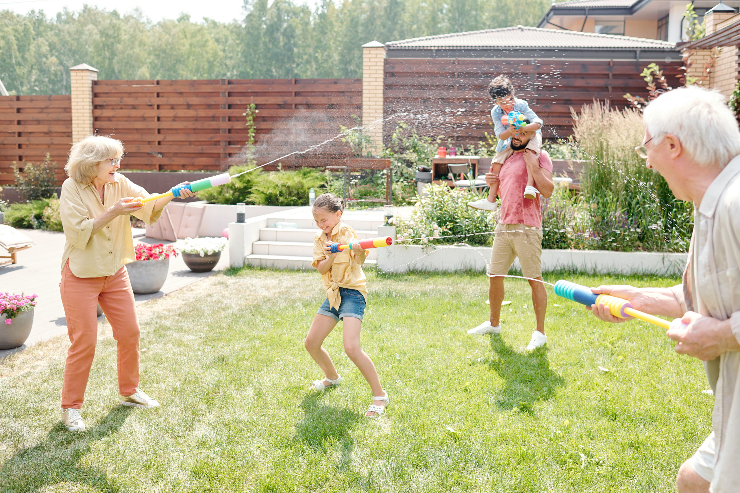 Familie beschießt sich mit Wasserspritzpistolen im Garten. Familie beschießt sich mit Wasserspritzpistolen im Garten.