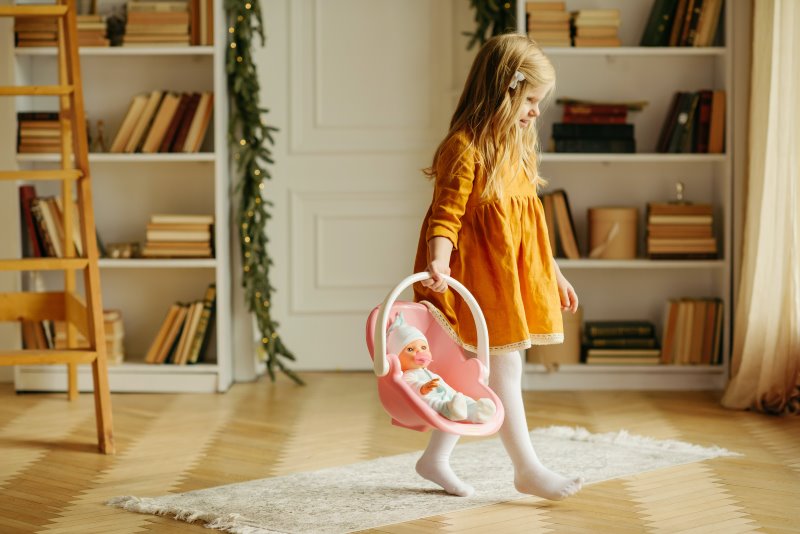 Puppenwagen Babyschale Mädchen trägt Puppenschale