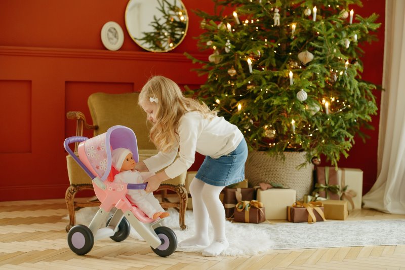 Puppenwagen Rollenspiel Mädchen kümmert sich um ihre Puppe.