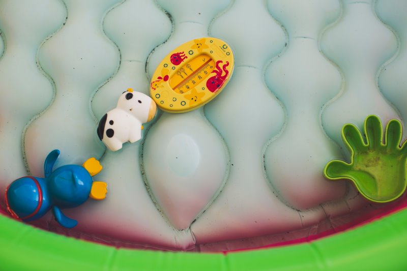 Wasserspielzeug und Thermometer im Planschbecken