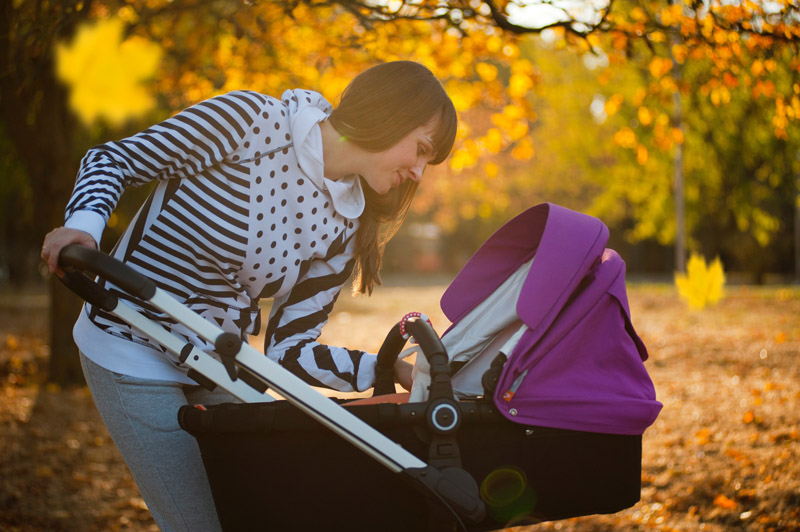 Baby-Kinderwagen im Test Eine Frau beugt sich über ihren Kinderwagen und schaut ihr Baby an.