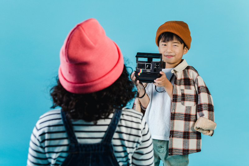 Freunde spielen gemeinsam mit einer Kinderkamera Junge nimmt Foto von Mädchen auf