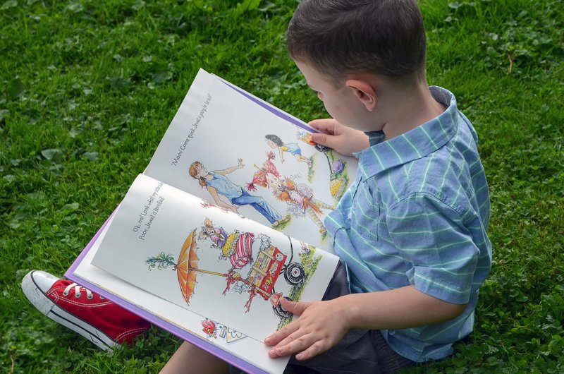 Kind liest ein Buch Ein Kind liest ein Kinderbuch