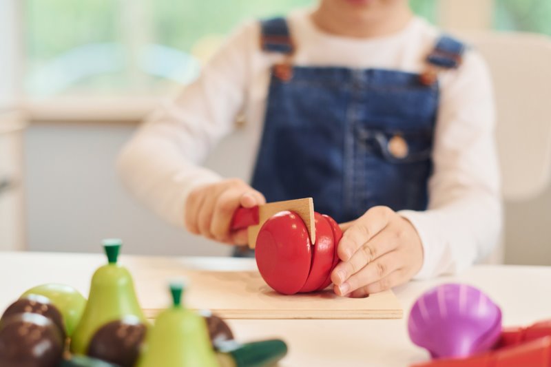 Kind schneidet Küchenspielzeug Ein Kind schneidet eine Spielzeug-Tomate.