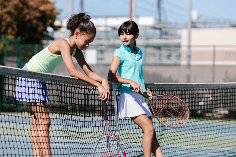 Tennis spielen mit Kinder-Sportbekleidung Mädchen beim Tennis in Kinder-Tennisbekleidung