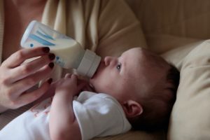 Baby wird von Mutter mit Anfangsmilch gefüttert.