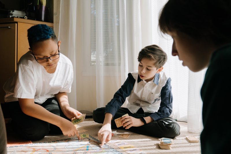 Kinder-Spielkarten mit der Familie. Kinder sitzen gemeinsam auf dem Boden und spielen Karten.