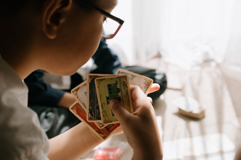 Kinder-Spielkarten Kind hält seine Spielkarten in der Hand.
