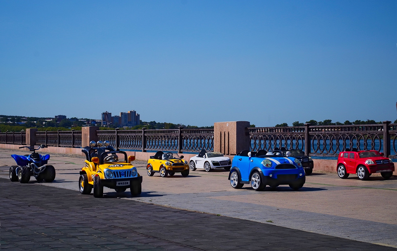 Mehrere Kinder-Elektroauto-Bautypen. Mehrere Kinder-Elektroautos unter einem blauen Himmel.