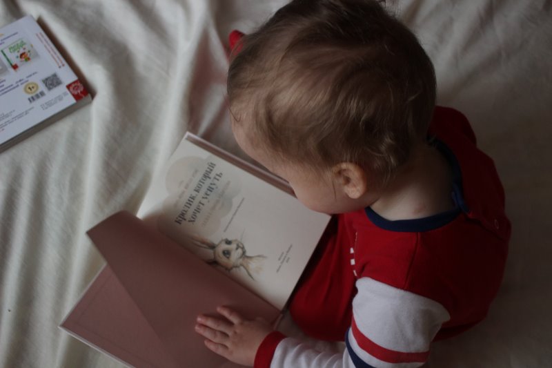 Kleinkind ließt Kinder-Buchklassiker Baby schaut ein Buch an