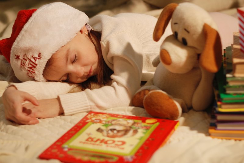 rotes Kinder-Weihnachtsbuch Mädchen schläft vor Weihnachtsbuch